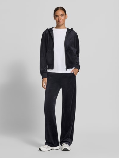 Frauenmodel trägt Straight Fit Sweatpants mit elastischem Bund Modell 'LOREN' von GUESS in Dunkelblau, glatte Oberfläche, Ganzkörperansicht von vorne. Material-Mix mit Stretch-Anteil für Damen.