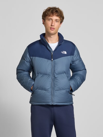 Männermodel trägt Regular Fit Jacke in Stepp-Optik Modell 'SAIKURU' von The North Face in Blau mit Logo-Stitching, Ganzkörperansicht von vorne. Kontext: Damen Jacke, Stehkragen, Rückenlänge 65 cm, Schulterbreite 47 cm, Brustweite 56 cm, Ärmellänge 67 cm.