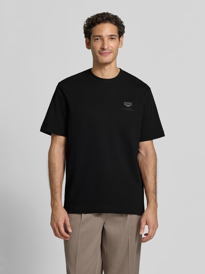 Männermodel trägt schwarzes Relaxed Fit T-Shirt aus reiner Baumwolle von Antony Morato mit Logo-Detail und Rundhalsausschnitt, Ganzkörperansicht von vorne. Rückenlänge bei Größe M: 69 cm.