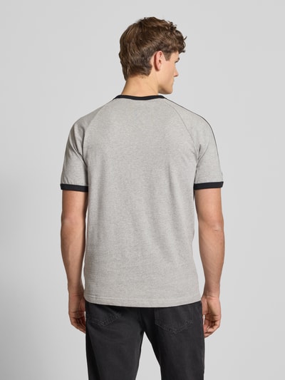 Männermodel trägt T-Shirt mit Label-Stitching von adidas Originals, grau, reine Baumwolle, Regular Fit, Rundhals, Ganzkörperansicht Rückansicht.
