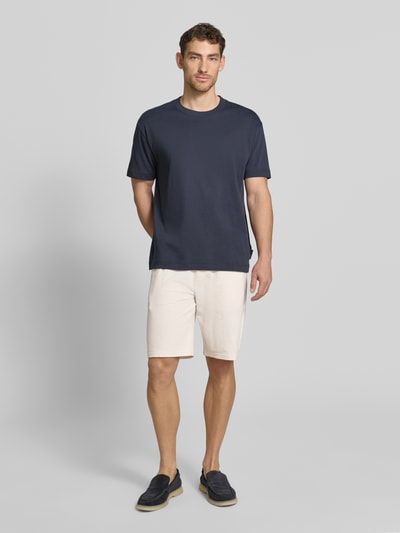 Männermodel trägt Relaxed Fit Sweatshorts aus reiner Baumwolle Modell 'DETROIT' von s.Oliver RED LABEL, Optik: Unifarben, Passform: Relaxed-Fit, fein strukturiert, Tunnelzug, Bundabschluss: elastisch, Eingrifftaschen, Gesäßtasche, Material: reine Baumwolle, Farbe hellbeige, Ganzkörperansicht von vorne.