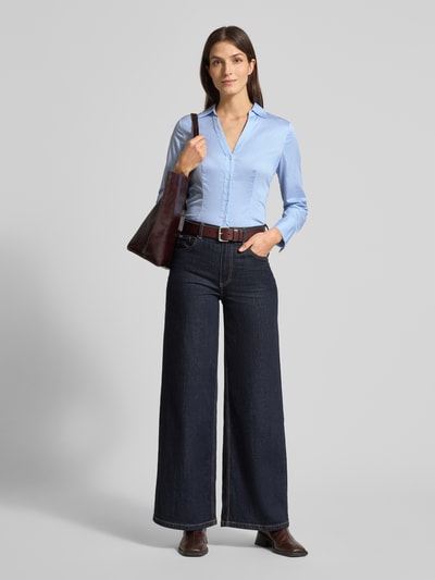 Kobiece modelka nosi Slim Fit Hemdbluse mit V-Ausschnitt od comma, bawełniany elastyczny materiał, krój slim fit, taliowany, długi rękaw, kołnierz koszulowy, zapięcie na guziki, długość pleców 64 cm, długość rękawa 61 cm, jasnoniebieski kolor, gładka tekstura, Ganzkörperansicht von vorne.
