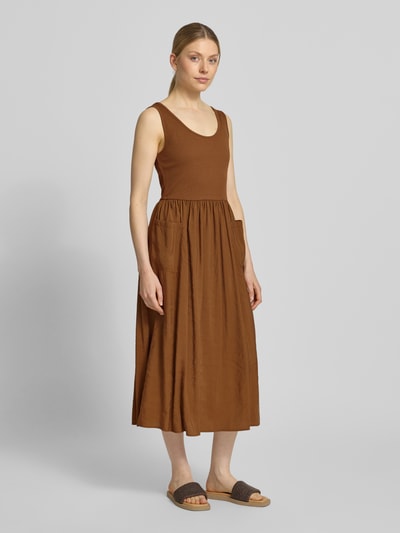 Frauenmodel trägt Midikleid mit aufgesetzten Taschen von Rich & Royal aus Micromodal-Mix, Taillierte Passform, Rundhalsausschnitt, Ärmelloses-Design, Rückenlänge bei Größe S: 114 cm, Brustweite bei Größe S: 32 cm, braune Farbgebung, weiche Textur, Ganzkörperansicht von vorne.