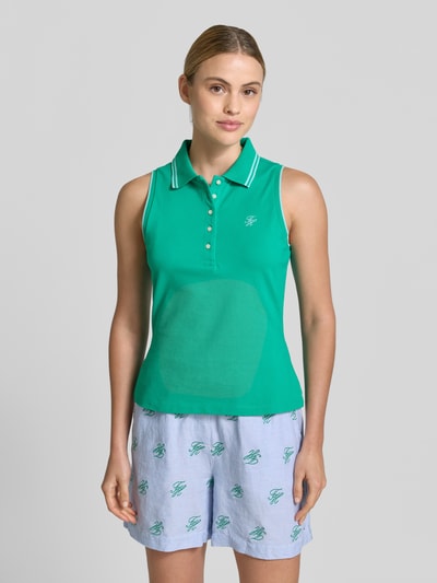 Frauenmodel trägt Slim Fit Poloshirt aus Baumwoll-Mix von Tommy Hilfiger in Two-Tone-Optik mit Logo-Stitching, Polokragen, Kontrast-Nähte, kurze Knopfleiste, ohne Ärmel, Ganzkörperansicht von vorne.