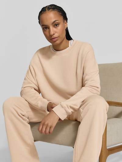 Frauenmodel trägt Oversized Sweatshirt aus Baumwoll-Mix von Juvia in Beige, Rundhalsausschnitt, Fleece-Innenseite, Nahaufnahme Oberkörper.