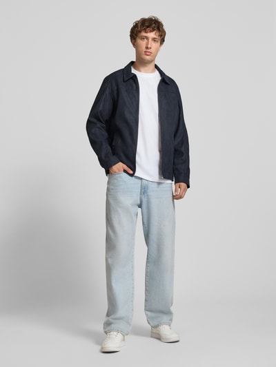 Männermodel trägt Regular Fit Jacke mit Umlegekragen Modell 'Dylan' von JACK & JONES in Leder-Optik, dunkelblau, Ganzkörperansicht von vorne.