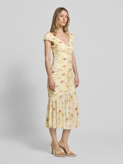Frauenmodel trägt Midikleid mit Drapierungen und V-Ausschnitt von Little Mistress, Material-Mix mit Stretch-Anteil, figurbetonter Schnitt, Rückenlänge bei Größe 36: 120 cm, sanfte Pastellfarben mit floralem Muster, feine Texturen, Ganzkörperansicht von vorne.