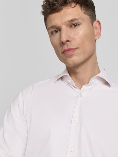 Männermodel trägt Regular Fit Businesshemd aus reiner Baumwolle von BOSS in Hellrosa, unifarben, Haifischkragen, Nahaufnahme Oberkörper.