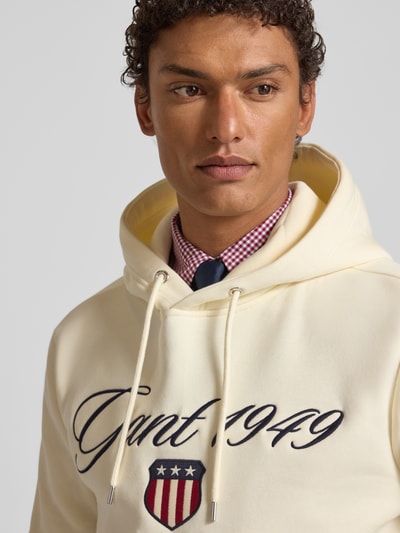 Männermodel draagt Hoodie met labelstitching en kangoeroezak van Gant, katoenmix, regular fit, beige tint, Nahaufnahme Oberkörper.