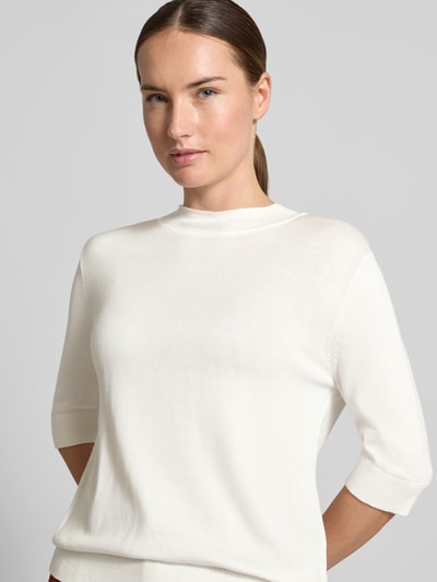 Frauenmodel trägt Strickpullover aus Viskose-Mix von MORE & MORE in Weiß, taillierte Passform, gerippte Abschlüsse, Nahaufnahme Oberkörper.