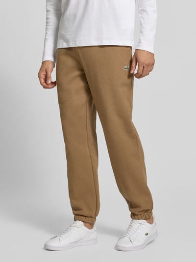Männermodel trägt Regular Fit Sweathose aus Baumwoll-Mix von Lacoste in Beige mit grünen Details, Nahaufnahme Unterkörper, Herren Sweathose von Lacoste.
