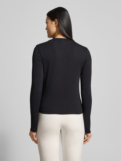 Frauenmodel trägt Longsleeve mit Label-Detail Modell 'SONIA' von Guess Activewear, schwarze Baumwolle, Regular Fit, Ganzkörperansicht Rückansicht.