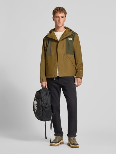 Männermodel trägt Jacke mit Label-Stitching Modell 'REIGN ON 2.0' von The North Face in Olivgrün, seitliche Taschen, Kapuze, Ganzkörperansicht von vorne, Regular Fit. Rückenlänge 69 cm, Schulterbreite 52 cm, Brustweite 63 cm, Ärmellänge 65 cm.