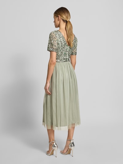 Frauenmodel trägt Knielanges Kleid mit floralem Pailettenbesatz von LACE & BEADS, tailliert, V-Ausschnitt, Mesh, Rückenansicht, Ganzkörperansicht.