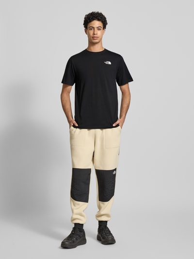 Männermodel trägt Regular Fit T-Shirt aus Baumwoll-Mix Modell 'VERTICAL' von The North Face in Schwarz mit Label-Print, Ganzkörperansicht von vorne. Herren T-Shirt, Rundhalsausschnitt, Rückenlänge bei Größe M: 71 cm.