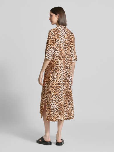 Frauenmodel trägt Tunikakleid aus Viskose im Allover-Look von Emily Van den Bergh, Gerader-Schnitt, 3/4-Arm, Midikleid, Rückenlänge 119 cm, Brustweite 46 cm, Ärmellänge 35 cm, braune Animalprint-Farben, weiche glatte Textur, Ganzkörperansicht Rückansicht.