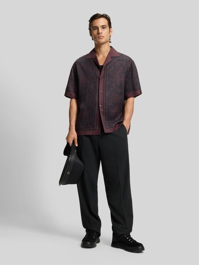 Männermodel trägt Regular Fit Anzughose mit Bügelfalten Modell 'FLIPS251X' von HUGO aus schwarzem Stretch-Twill, Ganzkörperansicht von vorne.