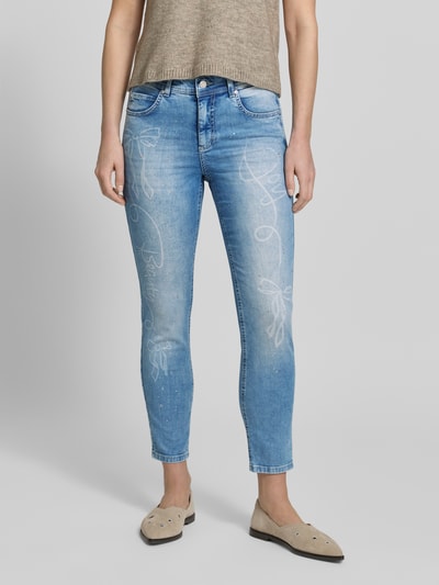 Frauenmodel trägt Slim Fit Jeans mit Strasssteinbesatz Modell 'Ornella Beauty' von Angels, hellblaue Jeans-Optik, Baumwoll-Mix mit Stretch-Anteil, 5-Pocket-Design, Knopf-Reißverschluss, Körpernaher-Schnitt, Nahaufnahme Oberkörper bis Knöchel, Bundweite 38 cm, Innenbeinlänge 67 cm, Größe 36. Ganzkörperansicht von vorne.