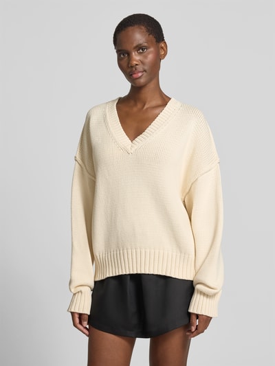 Frauenmodel trägt Oversized Pullover in Strick-Optik von black palms, cremefarben, V-Ausschnitt, Baumwoll-Mix, elastische Abschlüsse, Ganzkörperansicht von vorne. Rückenlänge bei Größe S: 64 cm.