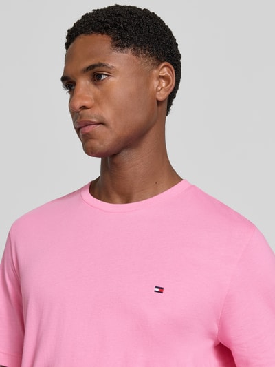 Männermodel trägt Regular Fit T-Shirt aus reiner Baumwolle von Tommy Hilfiger in Rosa, glatte Textur, Nahaufnahme Oberkörper, Herren T-Shirt von Tommy Hilfiger.