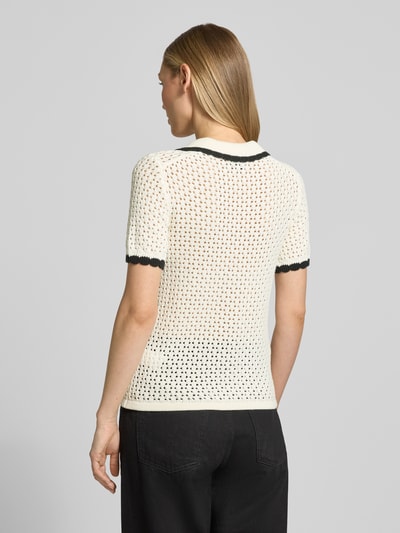 Vrouwenmodel draagt Slim Fit Poloshirt in Strick-Optik van Jake*s Casual, katoen, polokraag, korte mouwen, opengewerkt patroon, elastische boorden, kleur crème met zwarte accenten, geheel van achteren te zien, context: ruglengte maat S 53 cm, mouwlengte 24 cm.