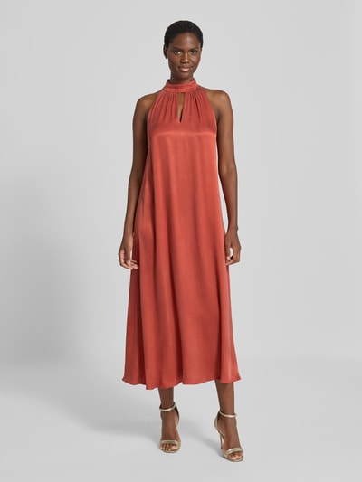Frauenmodel trägt Midikleid aus Viskose-Mix mit Neckholder von Jake*s Collection in rostrot, glatte Textur, Cut Out, Ganzkörperansicht von vorne.