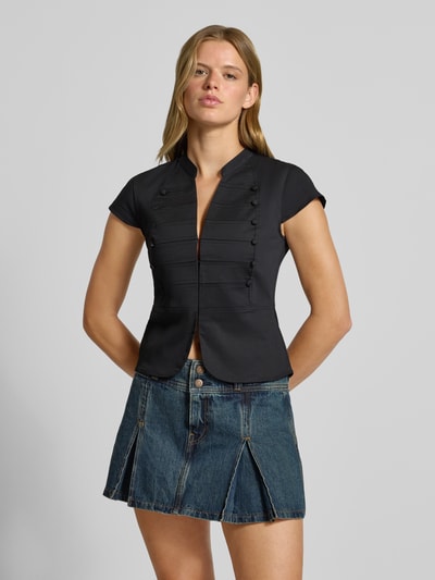 Frauenmodel trägt Slim Fit T-Shirt aus Baumwoll-Mix von Gina Tricot in Schwarz mit Stehkragen und V-Ausschnitt, Nahaufnahme Oberkörper.