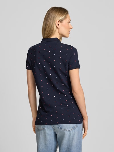 Männermodel trägt Poloshirt mit Polokragen und kurzer Knopfleiste von Christian Berg Woman, bawełniany miks z dodatkiem stretchu, krój regular fit, kolor granatowy z drobnym wzorem, długość pleców w rozmiarze S: 62 cm, całkowite ujęcie sylwetki z tyłu.