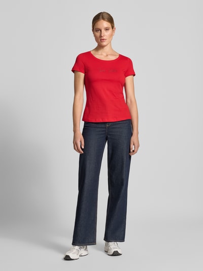 Frauenmodel trägt Regular Fit T-Shirt aus reiner Baumwolle von Tom Tailor in Rot und blaue Jeans, glatte Struktur, Ganzkörperansicht von vorne. Damen T-Shirt von Tom Tailor.