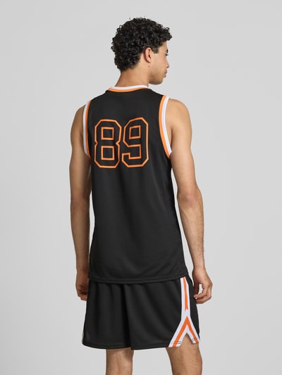 Männermodel trägt Regular Fit Top mit Logo-Print von KARL KANI, schwarzes Strukturmuster, Rundhalsausschnitt, Rückenlänge 75 cm, Ganzkörperansicht Rückansicht.