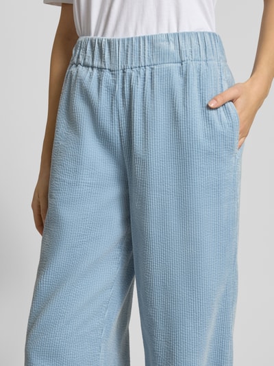 Frauenmodel trägt Relaxed Fit Cordhose aus reiner Baumwolle von Marc O'Polo Denim in Optik: Unifarben mit Struktur, Label-Stitching-Applikation, Bundabschluss: elastisch, seitliche Eingrifftaschen, Materialverarbeitung: Cord, Nahaufnahme Oberkörper.