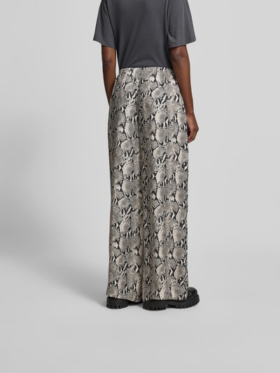 Frauenmodel trägt Stoffhose mit Viskose-Anteil von Anine Bing im Schlangenmuster, Cupro-Viskose-Mix, Relaxed-Fit, elastischer Bund, gerades Bein, Bundweite 38 cm, Innenbeinlänge 84 cm bei Größe S, Ganzkörperansicht Rückansicht.