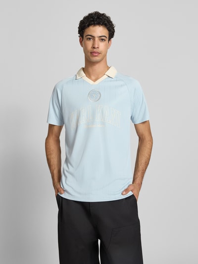 Männermodel trägt Regular Fit T-Shirt mit Umlegekragen Modell 'Heritage' von KARL KANI, hellblau mit Logo-Stitching, Rückenlänge bei Größe M: 70 cm, Ganzkörperansicht von vorne.
