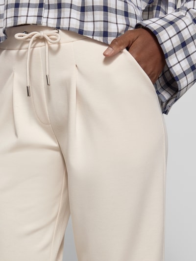 Frauenmodel trägt Sweatpants mit französischen Eingrifftaschen von monari in Creme, Material-Mix mit Viskose, Nahaufnahme Hüfte.