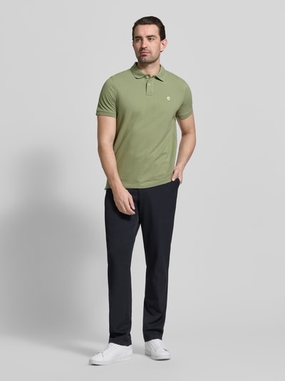 Männermodel trägt Slim Fit Poloshirt mit Logo-Stitching von MCNEAL in Grün, reine Baumwolle, Polokragen, Ganzkörperansicht von vorne.