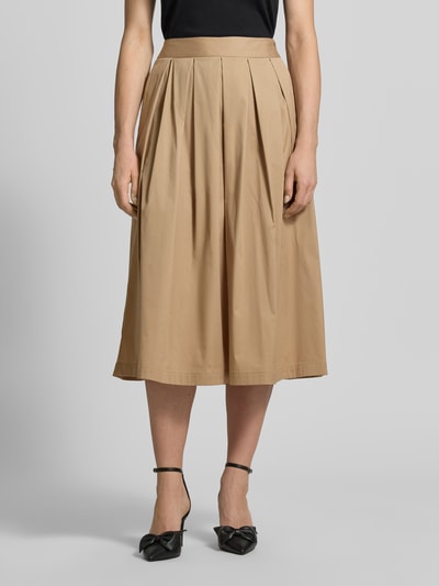 Frauenmodel trägt Midirock mit Eingrifftaschen Modell 'KYLIE' von 0039 Italy aus beigefarbenem Baumwoll-Mix mit Stretch-Anteil, A-Linie, Ganzkörperansicht von vorne.