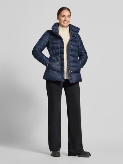 Kobiece model nosi Steppjacke mit Eingrifftaschen od Peuterey, granatowy kolor, pikowanie, stójka, wpuszczane kieszenie, Plisa, Ganzkörperansicht z przodu; krój slim fit, długość tyłu w rozmiarze 36: 72 cm, szerokość ramion w rozmiarze 36: 42 cm, szerokość w rozmiarze 36: 44 cm, długość rękawów w rozmiarze 36: 61 cm