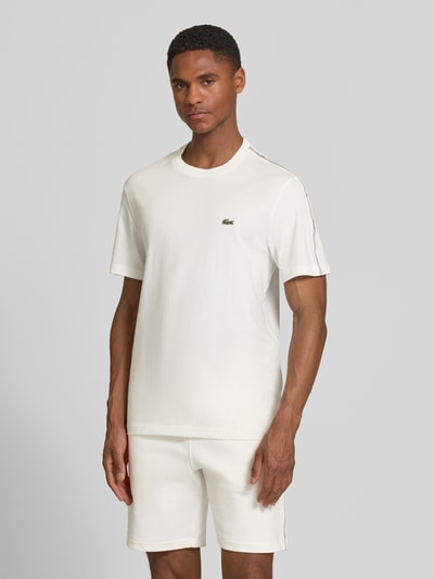 Mężczyznamodel nosi Regular Fit T-Shirt aus reiner Baumwolle von Lacoste, jednolity kolor, krój regular fit, okrągły dekolt, krótki rękaw, taśma z logo, materiał: czysta bawełna, Ganzkörperansicht von vorne.