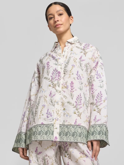 Frauenmodel trägt Florale Leinen Langarmbluse mit Lavendelprint von Christian Berg Woman, weiß mit lila Blumenmuster, Nahaufnahme Oberkörper.