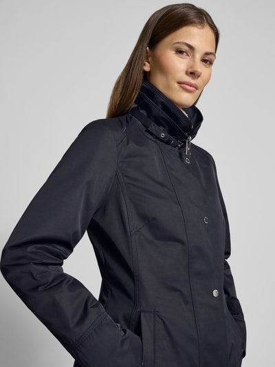 Frauenmodel trägt Trenchcoat mit Stehkragen und Eingrifftaschen von Fuchs Schmitt in Dunkelblau, Baumwoll-Mix, Nahaufnahme Oberkörper.
