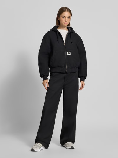 Vrouwenmodel draagt Straight Fit broek met ritssluiting Model 'Omak' van Carhartt Work In Progress, zwart, katoenmix, steekzakken, achterzakken, bandwijdte maat 27 42 cm, binnenbeenlengte maat 27 80 cm, full body vooraanzicht.