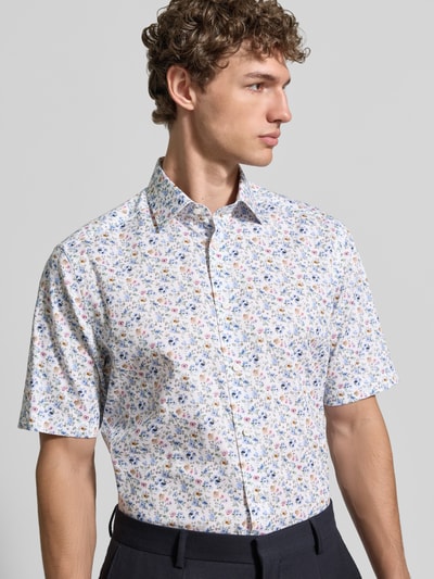 Männermodel trägt Regular Fit Freizeithemd mit Kentkragen von OLYMP, floraler Allover-Print, durchgängige Knopfleiste, kurzärmelig, Ganzkörperansicht von vorne.