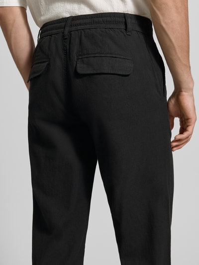 Männermodel trägt Hose aus Leinen-Baumwoll-Mix mit elastischem Bund von Lindbergh, Regular-Fit, schwarze Farbe, Detailaufnahme Rückansicht. Herren Hose mit Eingrifftaschen, Bundweite 40 cm, Innenbeinlänge 79 cm, Größe M.