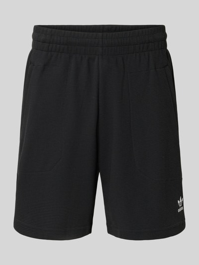 Produktfoto, Relaxed Fit Sweatshorts mit Baumwoll-Anteil von adidas Originals in Schwarz, unifarben, Waffelstruktur, Logo-Stitching, elastischer Bund, seitliche Reißverschlusstaschen