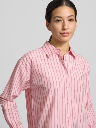 Modelka nosi Hemdbluse mit Knopfleiste Modell 'BARDOT' od Soyaconcept, różowy z białymi paskami, mieszanka materiałów, luźny krój, kołnierz koszulowy, długość tyłu 57 cm, długość rękawa 56 cm, ujęcie: zbliżenie górnej części ciała.