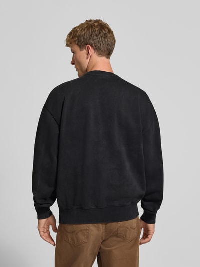 Männermodel trägt Relaxed Fit Sweatshirt aus Baumwoll-Mix von PEGADOR in Schwarz mit gerippten Bündchen und Logo-Stickerei, Ganzkörperansicht Rückansicht.