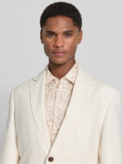 Männermodel trägt Slim Fit Freizeithemd aus Viskose-Baumwoll-Mix Modell 'JSH-278Pio' von JOOP! COLLECTION in Beige mit Paisleymuster, Nahaufnahme Oberkörper.