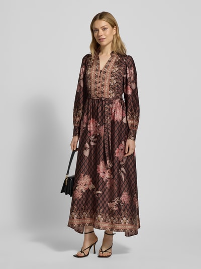 Frauenmodel trägt Maxikleid aus Satin mit Bindegürtel von Neo Noir in Schwarz mit floralen Mustern, A-Linie, V-Ausschnitt, Knopfleiste, Ganzkörperansicht von vorne.