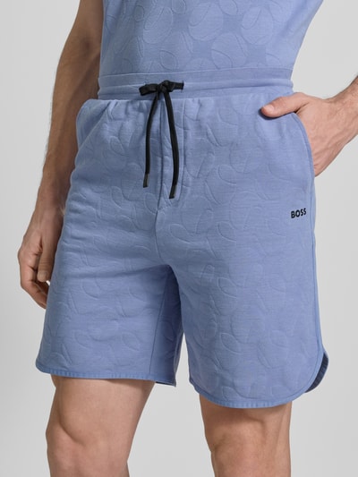 Männermodel trägt Regular Fit Shorts aus Baumwoll-Mix Modell 'JT_Member Short' von BOSS Green, Optik: Unifarben, grafisch strukturiert, seitliche Eingrifftaschen, elastischer Bundabschluss, Materialverarbeitung: Sweat, Nahaufnahme Oberkörper.