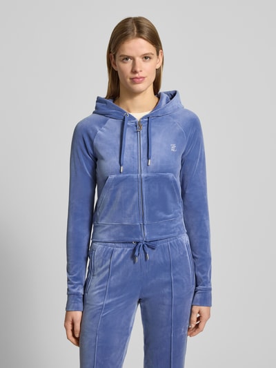Frauenmodel trägt Juicy Couture Sweatjacke mit Kapuze Modell 'MADISON' im Slim-Fit aus Material-Mix mit Stretch-Anteil, Reißverschluss, Tunnelzug, Eingrifftaschen, Label-Detail, blaue Farbgebung, samtige Textur, Nahaufnahme Oberkörper.